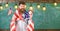 Man with beard on cheerful face holds flag of USA and clock, chalkboard on background, copy space. American educational