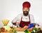 Man with beard cuts carrot with knife on white background