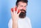 Man beard hipster strawberries between fingers blue background. Carbohydrate content strawberry. Mostly carbohydrates