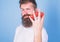 Man beard hipster strawberries between fingers blue background. Carbohydrate content strawberry. Mostly carbohydrates