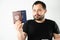 A man with a beard holding a passport of Russia and Ukraine translation: - Ukraine. Passport, Russian Federation