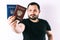 A man with a beard holding a passport of Russia and Ukraine translation: - Ukraine. Passport, Russian Federation