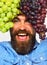 Man with beard holds bunches of black and green grapes