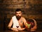 Man with beard holds glass of wine on wooden background