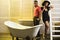 Man with beard and lady in hat with glass of champaign in bathroom. Couple on calm faces relaxing in bathroom. Luxury