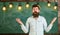 Man with beard and mustache on confused face stand in front of chalkboard. Difficulties concept. Guy bewildered with