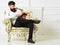 Man with beard and mustache sits on armchair and reading, white wall background. Connoisseur of literature concept