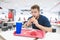 Man with a beard sits at a table with a tray in a fast-food restaurant with a burger in his hands