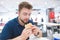 Man with a beard sitting in a bright fast food restaurant and looking at the burger in his hands with appetite