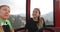 A man with a beard and two women sit in the cabin of the cable car and climb the mountains.