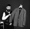 Man with beard in vest by clothes rack. Official wardrobe choice concept. Businessman with serious face tries jacket on