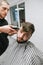 Man with a beard visits a barber shop, a barber repeats creating a hairstyle with a clipper in his hands. Professional hairdresser