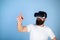 Man with beard in VR glasses, light blue background. Interactive surface concept. Guy with head mounted display interact