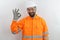 Man with beard wearing hardhat, safety goggles and reflecting jacket, smiling positive doing ok sign with hand and fingers.