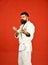 Man with beard in white kimono on red background