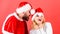 Man with beard and woman santa hat red background. Christmas masquerade karnival concept. Couple cheerful face celebrate