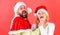 Man with beard and woman in santa hat on red background. Couple celebrate winter holiday christmas. Christmas masquerade