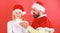 Man with beard and woman in santa hat on red background. Girl disgusted face celebrate christmas. Couple celebrate