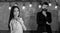 Man with beard and young lady teacher stand in classroom, chalkboard on background. Lady teacher and bearded hipster