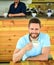 Man bearded guy drinks cappuccino wooden table cafe. Cafe visitor smiling face enjoy coffee drink. Many ways to enjoy