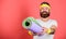 Man bearded happy athlete hold mat red background. Athlete coach ready for training. Old school aerobics concept