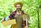 Man bearded hipster collecting harvest. Ranch man. Organic farm. Gardener hold box with gardening tool. Gardening advice