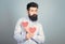 Man bearded hipster with heart valentine card. Celebrate love. Guy attractive with beard and mustache in romantic mood