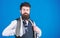 Man bearded hipster hold few neckties on blue background. Guy with beard choosing necktie. Gentlemens guide. How to