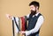 Man bearded hipster hold few neckties. Guy with beard choosing necktie. Perfect necktie. Select tie that has colors of