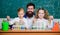 Man bearded teacher work with microscope and test tubes in biology classroom. School biology experiment. Explaining