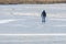 Man from behind standing on the ice of a frozen lake, happy winter activity or dangerous daring in thawing weather, copy space