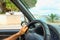 Man behind the wheel of a car. Outside the car window of palm trees and sea. Bright southern sun