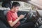 Man behind the wheel of his car loses concentration on the road situation and gets stuck in a smartphone typing SMS in a chat.