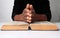 Man with a bible praying with hands clenched together