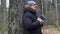 Man with Bible and rosary praying near tree