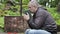 Man with Bible and rosary praying at outdoors church near cross