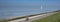 man on bicycle track and lonely sailing boat on vast empty blue lake in zeeland