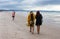 Man with big scarf and dreadlocks and woman in dress and long red hair walk along beach in Byron Bay NSW Australia Aug 28 2014