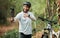Man, bike and forest with selfie, smile and pointing with wellness, training and exercise on adventure. Influencer guy