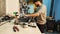 A man bike mechanic with a beard assembles a mountain bike in his workshop.