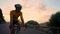 A man on a bike rides looking at the camera at sunset on a mountain road. Slow motion steadicam