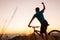 Man biker man meets a sunset in top of hill. He rising a one arm greeting on another successful day ending. Active sport people