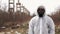 Man in bio-hazard suit and gas mask stands before the factory