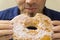 Man bite huge doughnut in his hands, sugar on his face