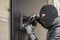 Man in a black balaclava mask opens a locked door with a lock pick. The robber breaks into the house. Robbery of a private house.