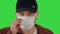 Man in black baseball cap with a medical mask on his face on a Green Screen, Chroma Key.