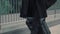 Man in black coat with suitcase walking on background of airport