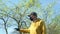 Man in black disposable mask waves hand by green trees