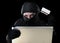 Man in black holding credit card using computer laptop for criminal activity hacking password and private information