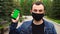 Man in black medical mask showing mobile phone with green screen outdoor with a green background
